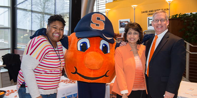 Two women and a man pose at an Orange Success event with University mascot Otto the Orange
