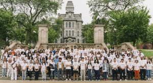Group of students in SummerStart t-shirts standing together, with Hall of Languages building in background.