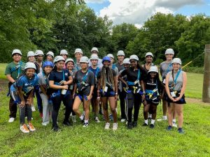 A group of students standing together outside, wearing helmets and harnesses.