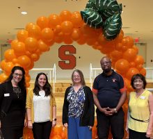 Five members of the retention and student success staff in front of a balloons made to look like an orange.